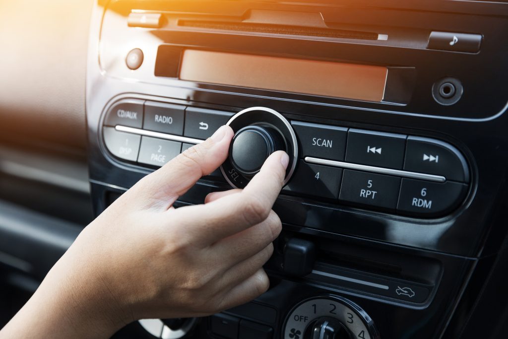 mulher aumentando o volume do rádio do carro para ouvir rádio e aumentando a audiência em rádio