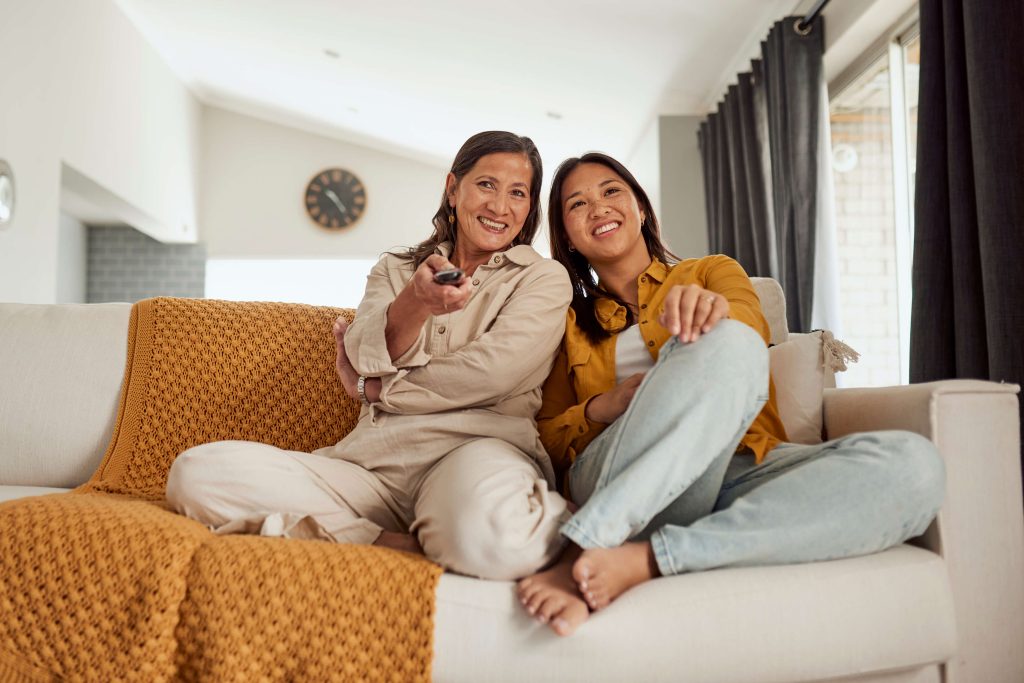 Duas mulheres relaxando em um sofá e assistindo TV.