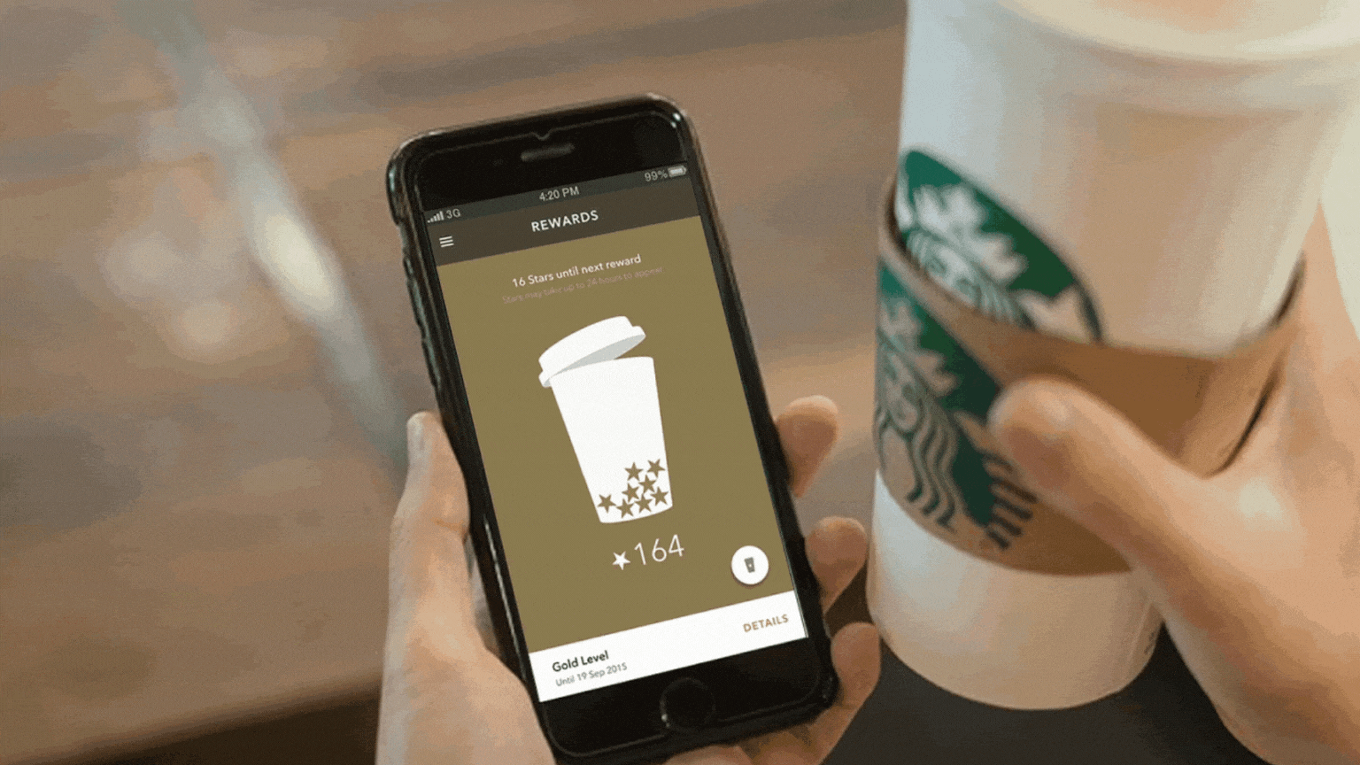 Nesta imagem podemos ver uma pessoa segurando uma bebida do Starbucks enquanto mexe no site da mesma marca. O site do Starbucks faz uso de inteligência artificial para entregar resultados mais personalizados a seus clientes.