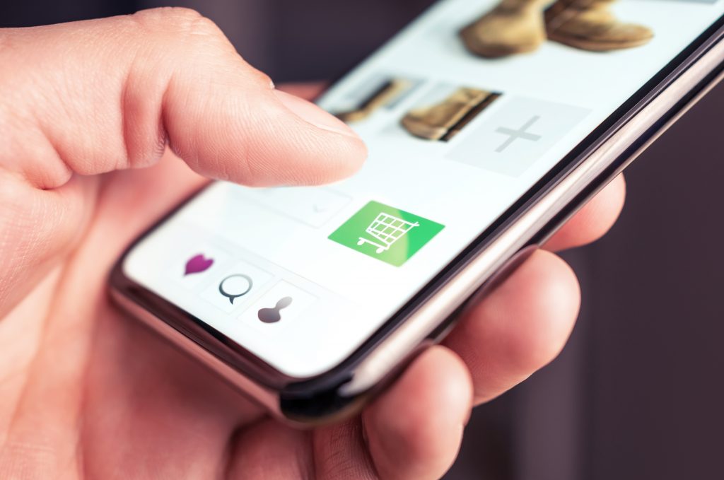 Nesta imagem podemos ver a tela de um celular e uma pessoa que está a ponto de efetuar uma compra.Essa compra pode ser impulsionada por meio da produção de conteúdo comprável.