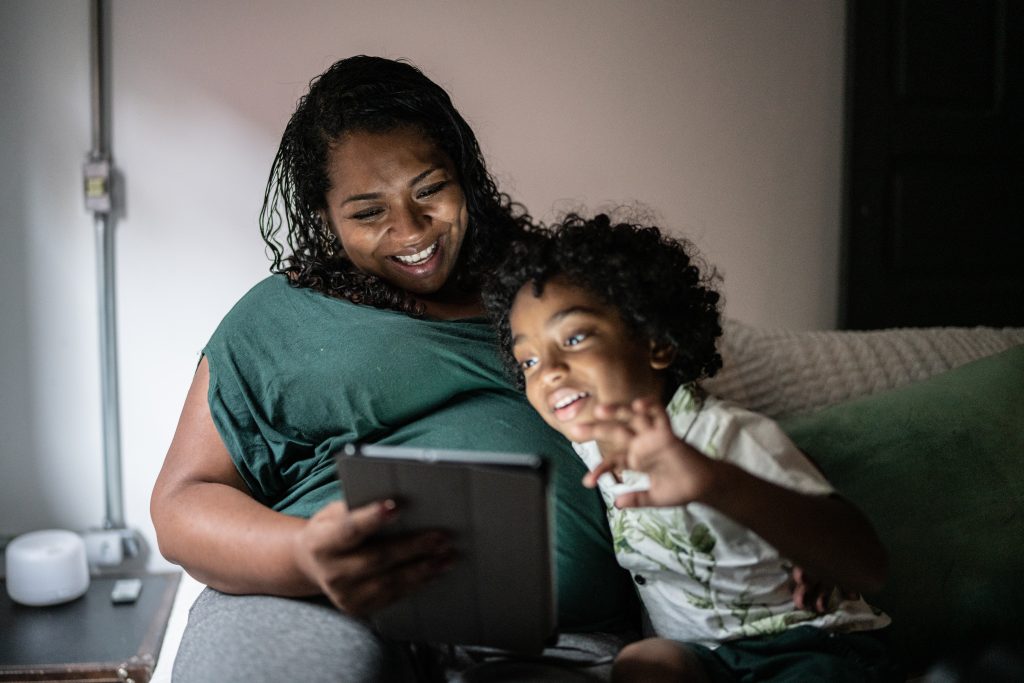 Nesta imagem temos uma mulher e seu filho olhando anúncio de display na tela do tablet.