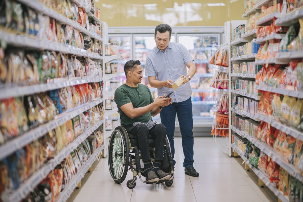 Nesta imagem podemos ver um homem em sua cadeira de rodas, enquanto faz compras.