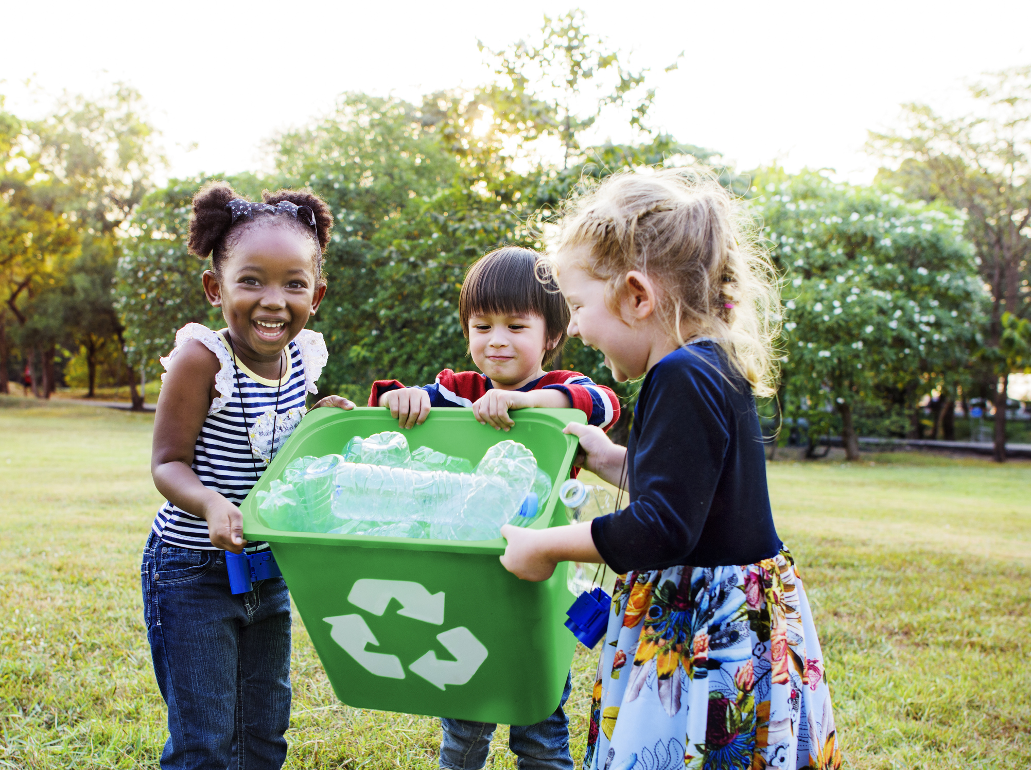 Nesta imagem podemos ver crianças da Geração Alpha juntando o lixo do parque e colocando na lixeira.