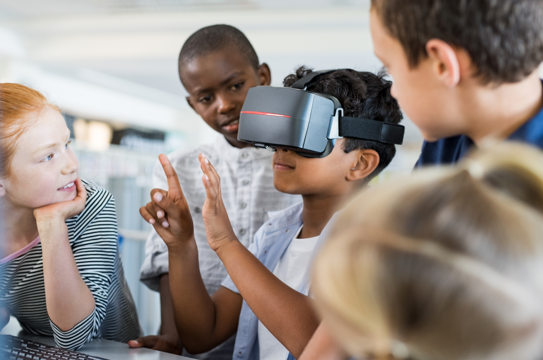 Nesta imagem podemos ver crianças da Geração Alpha reunidas para discutir alguma coisa e fazem uso de um óculos de realidade virtual.
