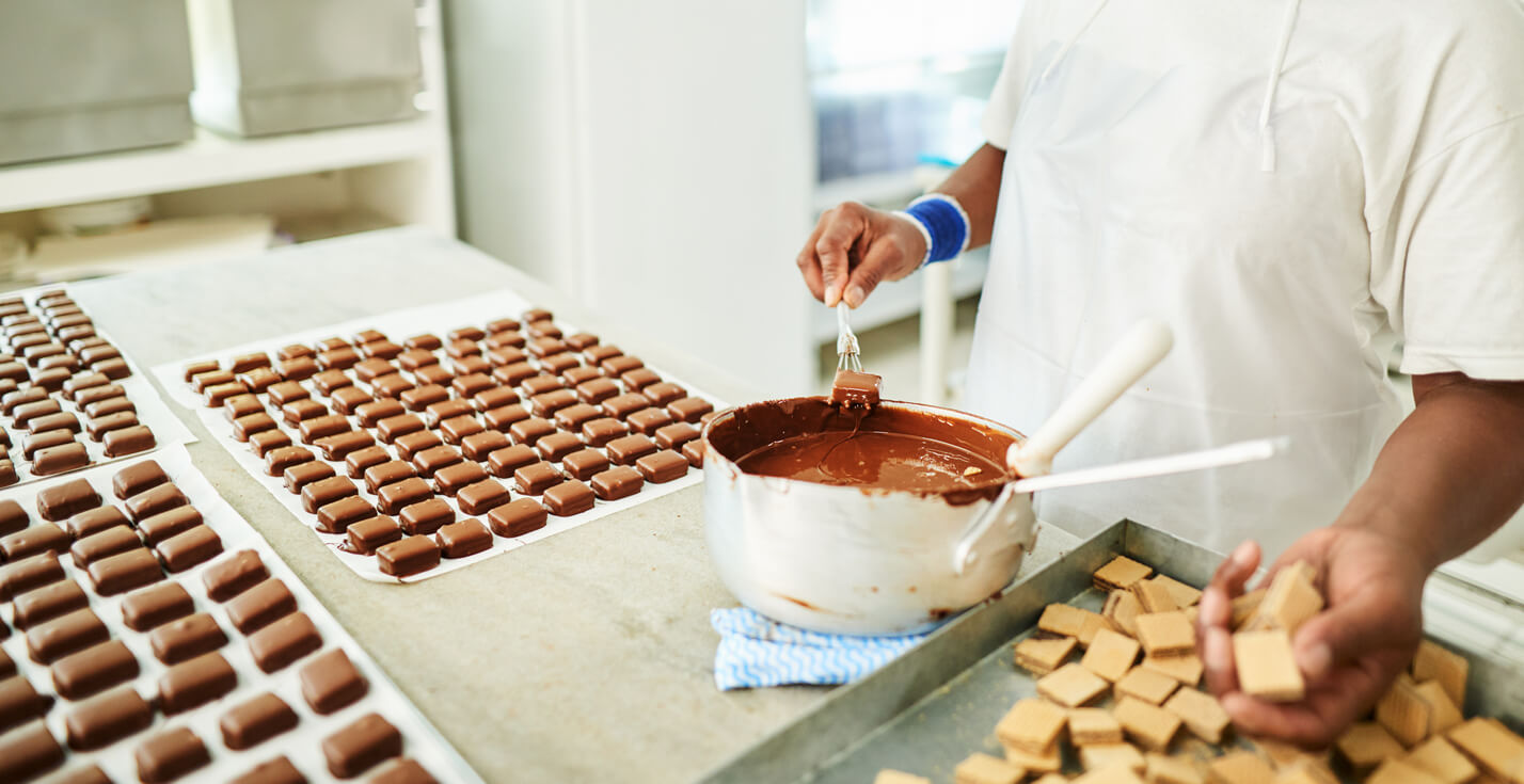 Fábrica de chocolate. ideias para vender na Páscoa. Pessoa na fabrica de chocolate preparando doces