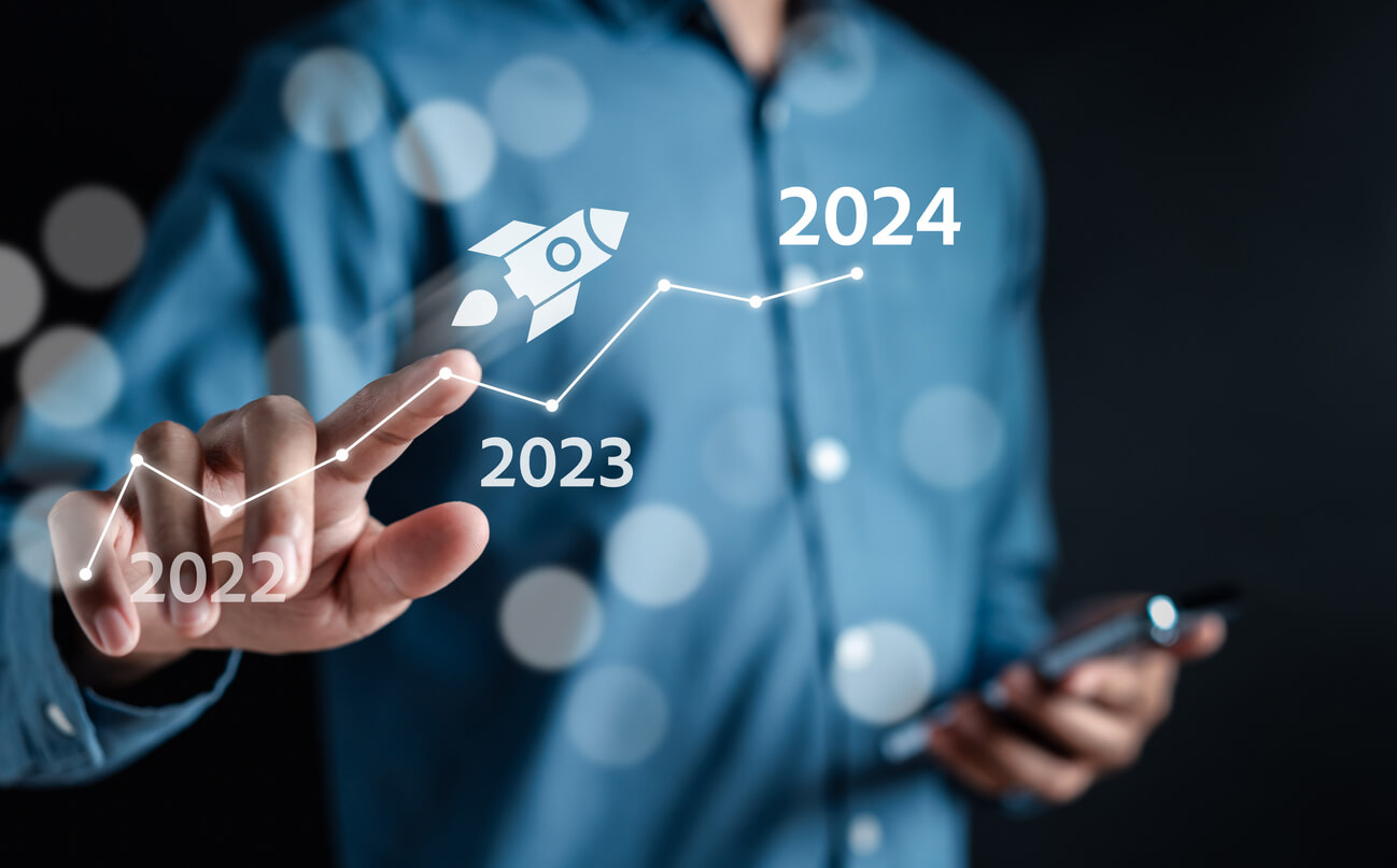 Planejamento de marketing 2024. Na foto vemos uma imagem de uma pessoa apontando para um grafico de 2023 para 2024