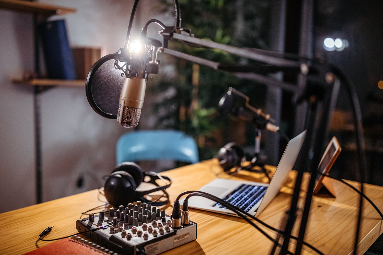 Mesa de podcast com microfone, notebook e fones de ouvido