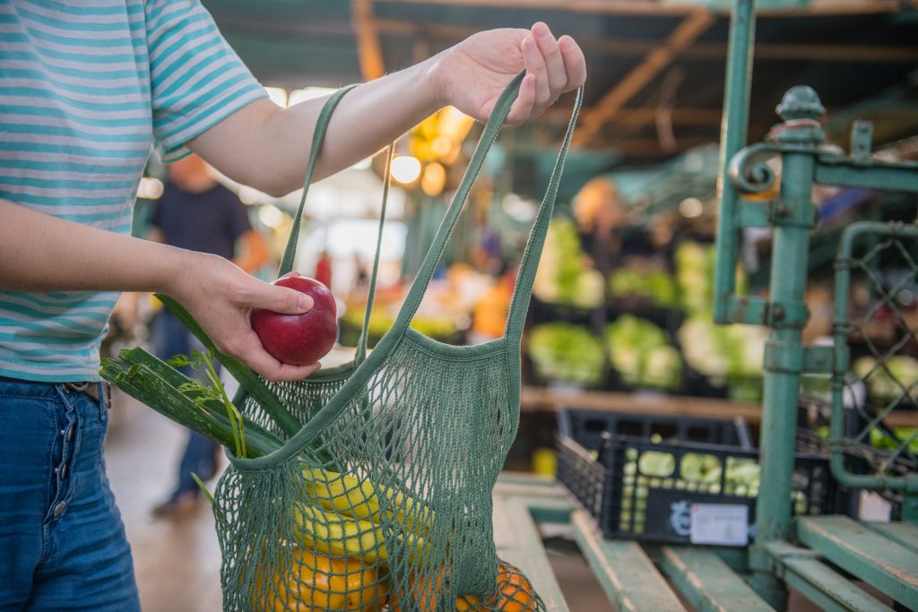 Frutas e legumes em um saco de malha de algodão reutilizável, zero de compras de resíduos no mercado ao ar livre.