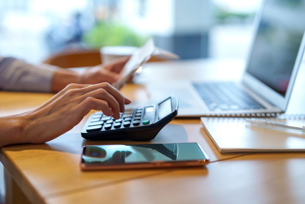 Foto cortada de mulher asiática sentada à mesa fazendo plano financeiro e orçamento com calculadora e laptop.