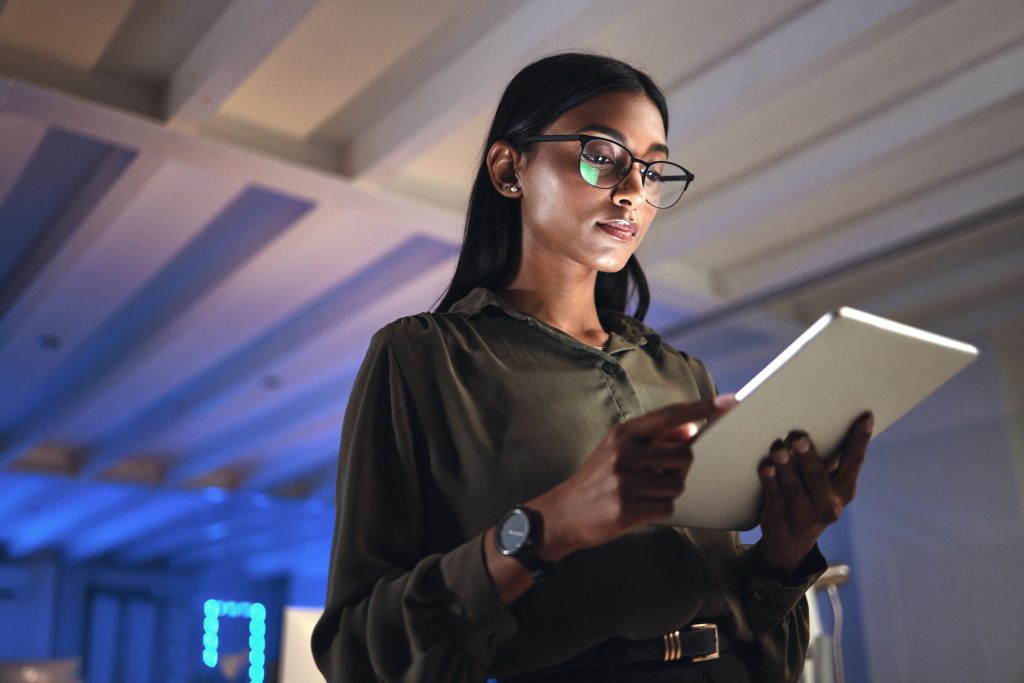 Tablet, designer e mulher séria pesquisam em escritório de startup de negócios à noite no prazo.