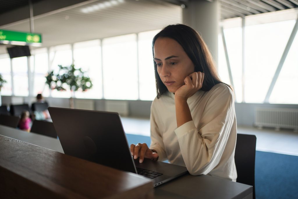 Mulher trabalhando em laptop no aeroporto.