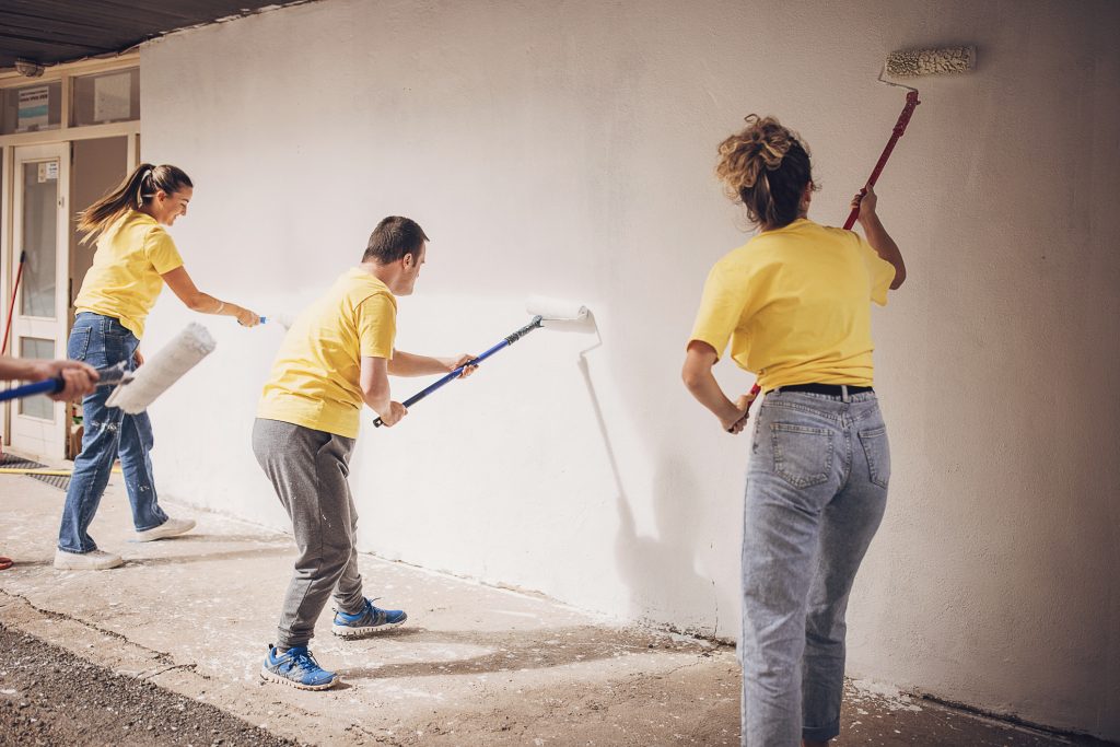 Pessoas pintando parede de construção.