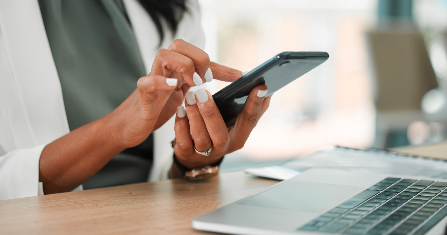 Mulher com as unhas brancas mexendo no celular conferindo se o site é responsivo e usando o computador também para verificar o site