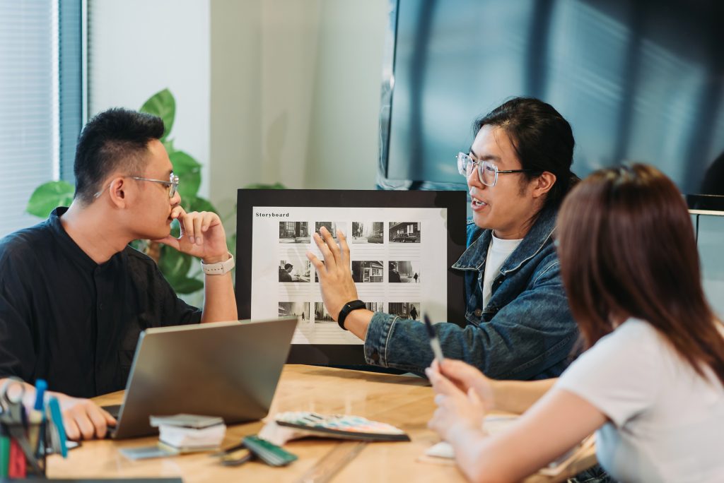 Asiático chinês bonito jovem adulto dando apresentação com a equipe no estúdio de design.