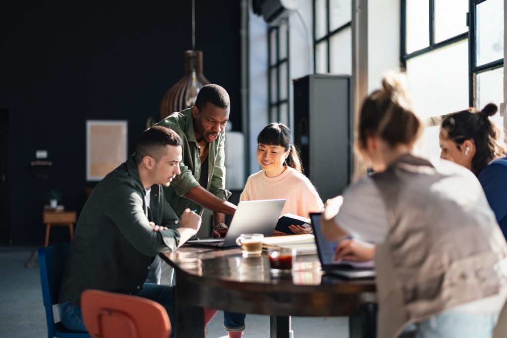 Equipe diversificada trabalhando em conjunto no espaço de coworking moderno.