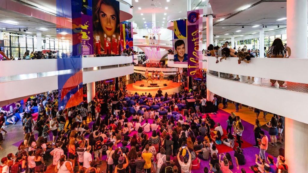 Evento presencial realizado em um shopping, onde vários jovens formam uma multidão. Esse é o TUDUM, que reúne experiências de marca.