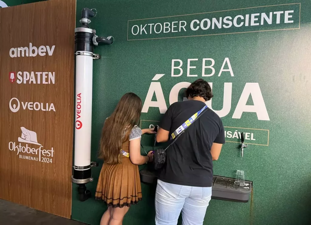 Casal com roupas típicas alemãs está enchendo a caneca de água na Oktoberfest.