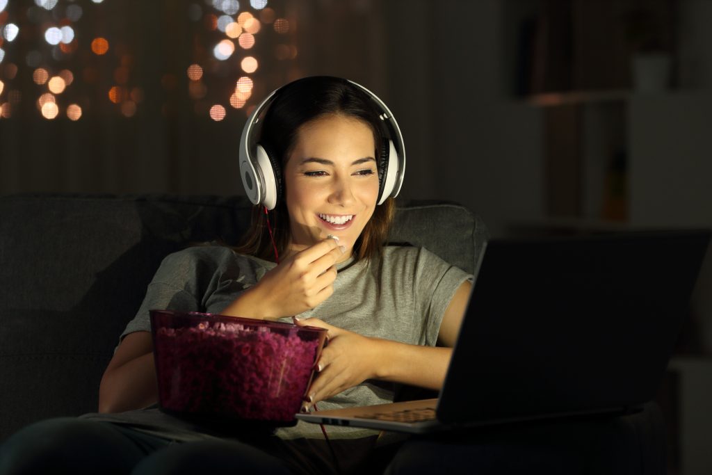 Mulher assistindo no computador, online, na noite.