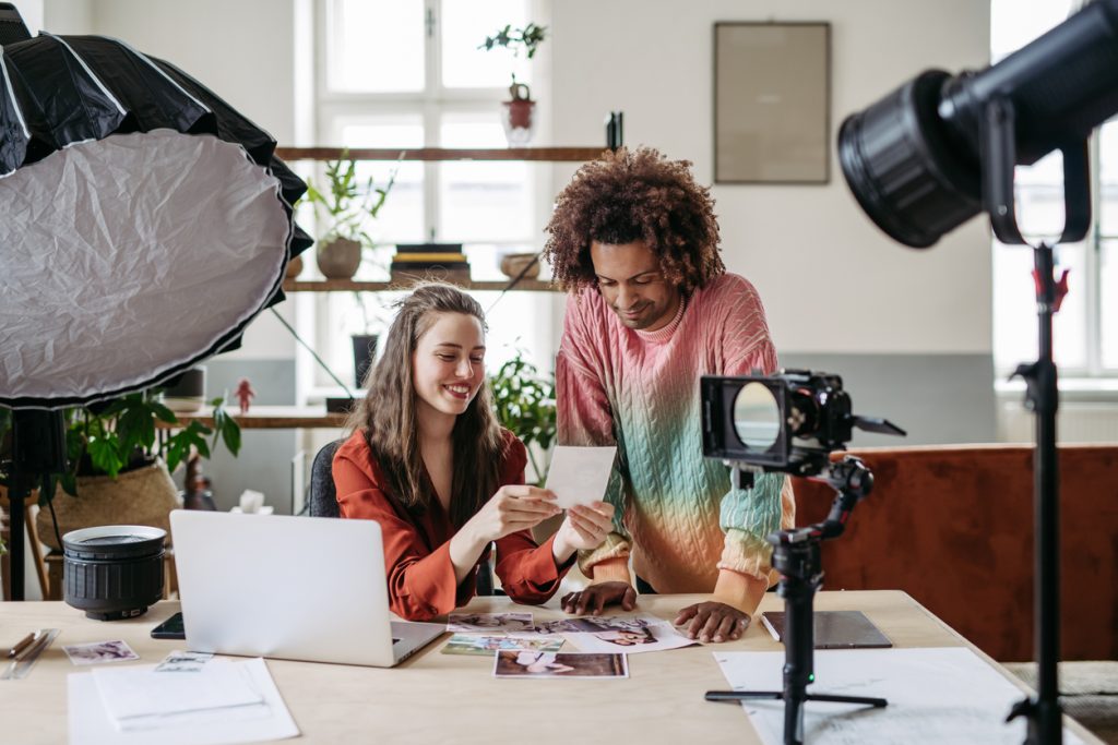 Jovens colegas trabalhando juntos em ateliê fotográfico. Eles estão se preparando para uma live streaming.