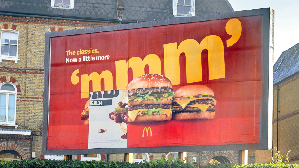 Outdoor do McDonald's com três sanduíches. Uma peça do outdoor está faltando, revelando um outro tipo de sanduíche embaixo.