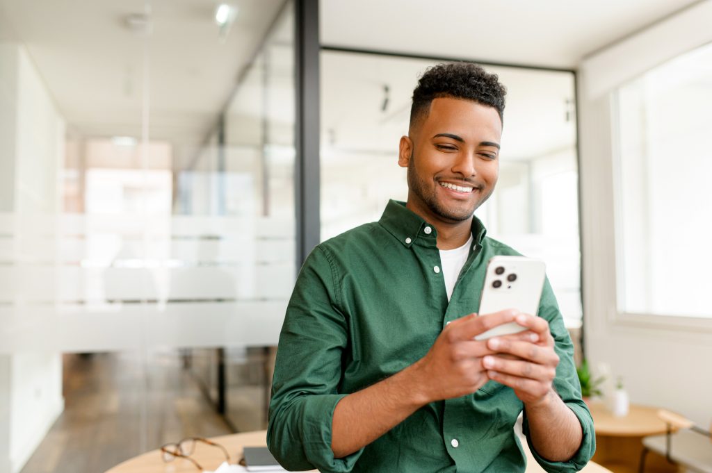 Jovem indiano do sexo masculino, freelancer, empresário está com um smartphone na mão.