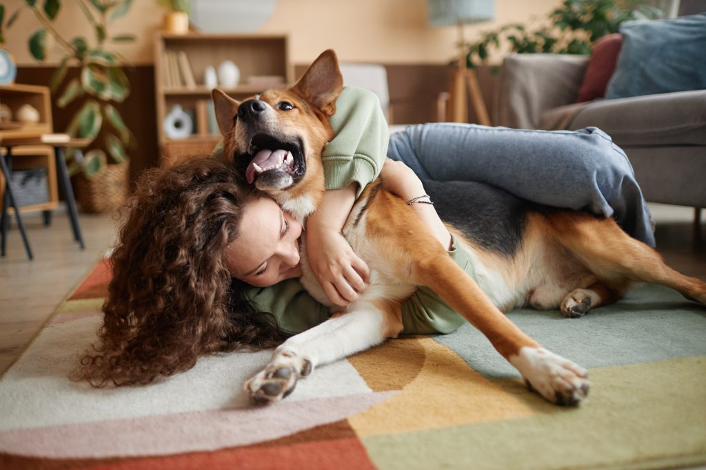 Menina brincando com cachorro feliz brincando no chão em casa.