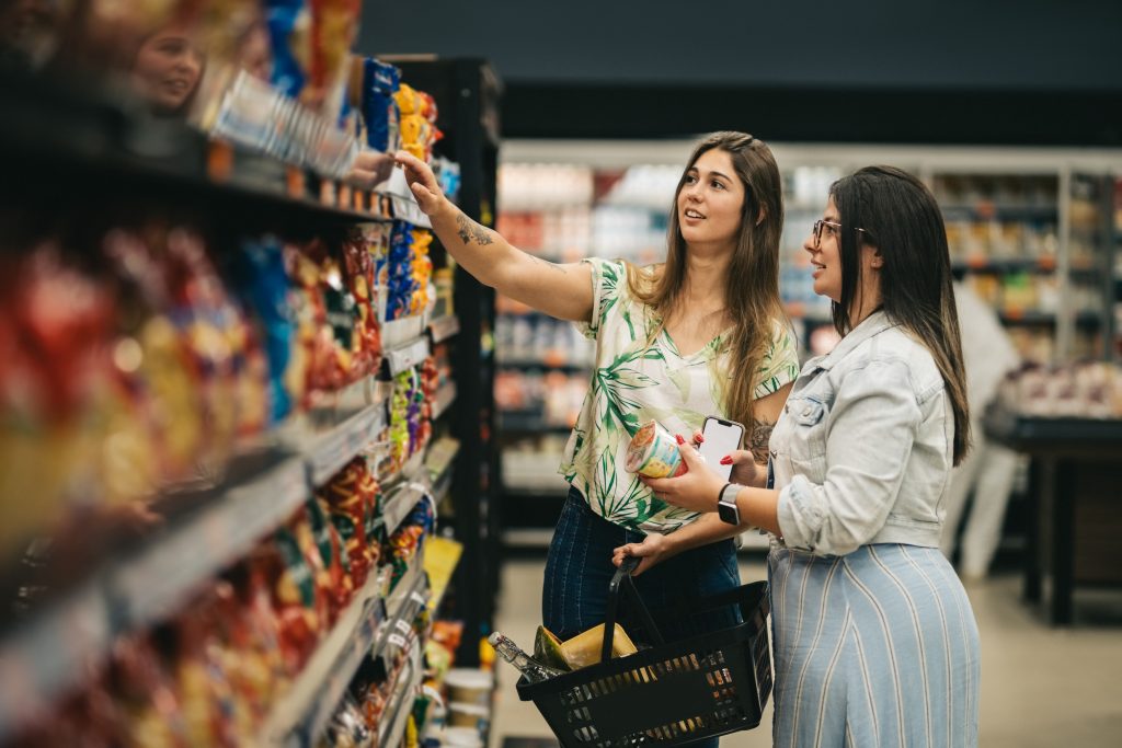 Duas amigas fazendo compras no supermercado. Lá tem o produto que elas querem porque é de uma marca que possui disponibilidade mental e física.