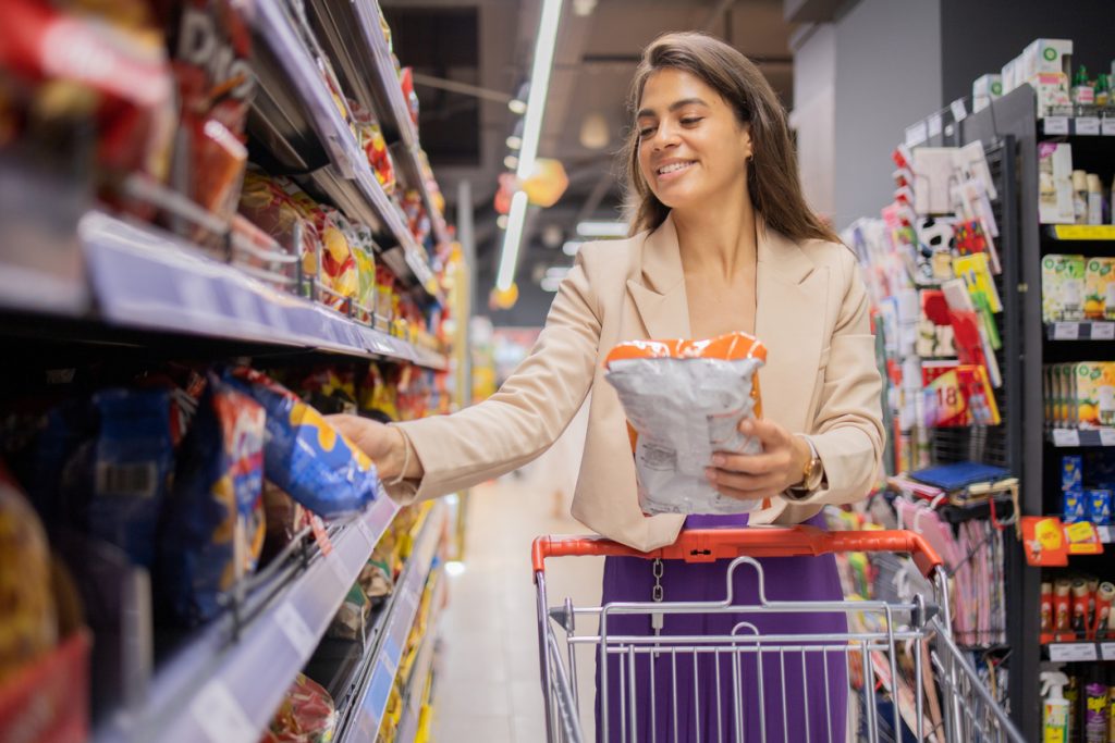 Mulher jovem feliz que compra mantimentos.