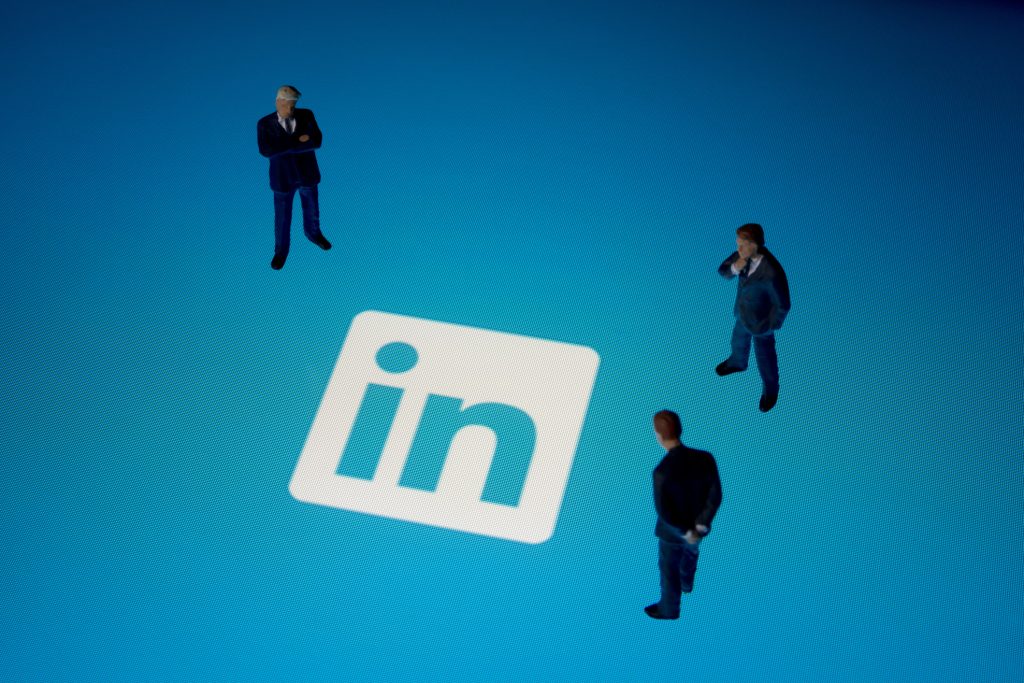 Três bonequinhos olhando a logo do LinkedIn Ads.