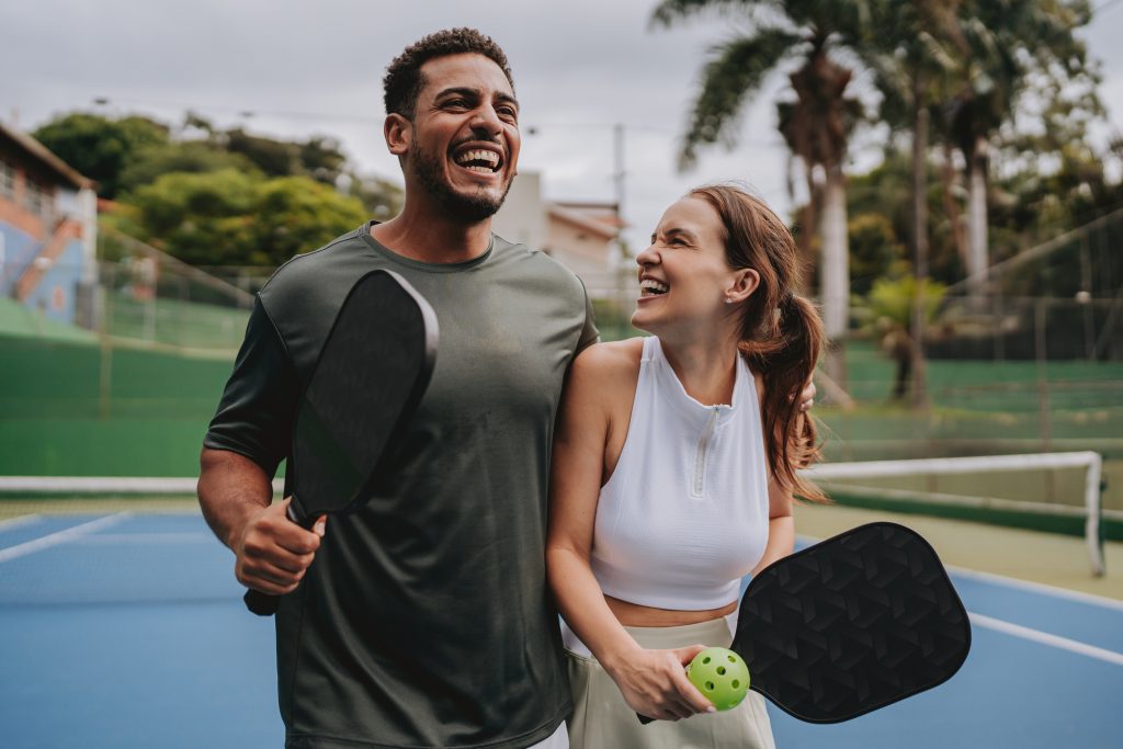 Casal jogando pickleball comemorando ponto.