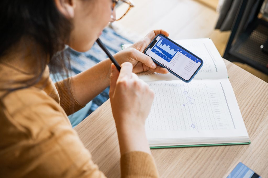 Empresária analisando mercado financeiro de ações em smartphone.