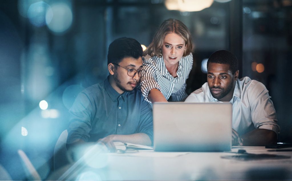Tiro cortado de três jovens empresários trabalhando juntos em um laptop em seu escritório tarde da noite.