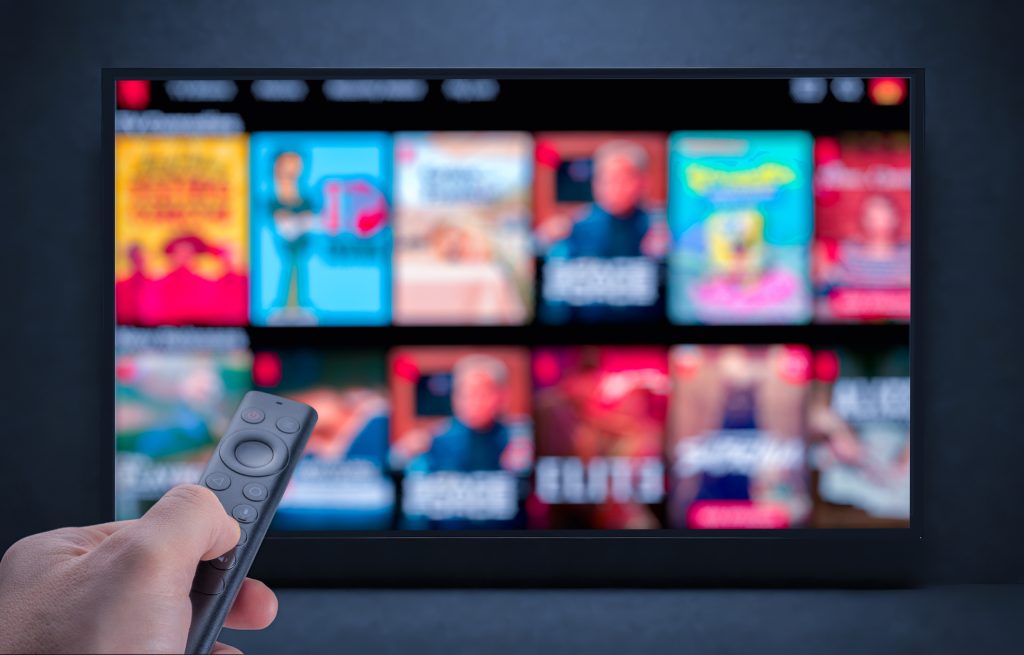 Mão masculina segurando o controle remoto da TV.