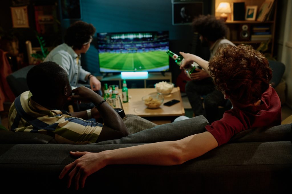Homens jovens assistindo jogo de futebol na TV