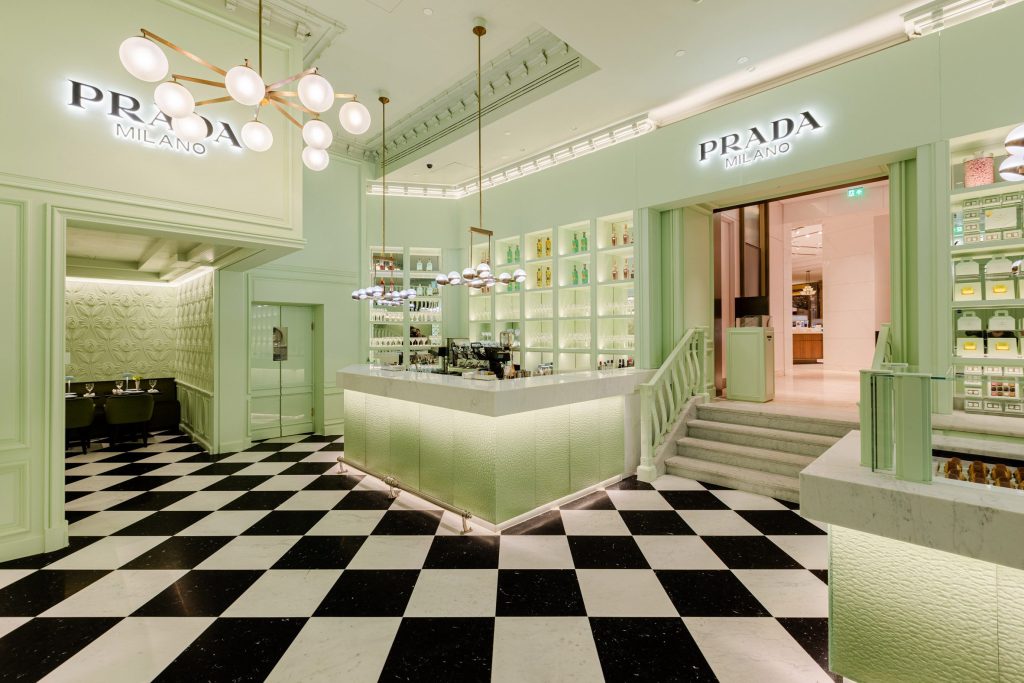 Cafeteria com chão xadez e móveis em verde pistache. Um case de marketing de luxo da Prada.
