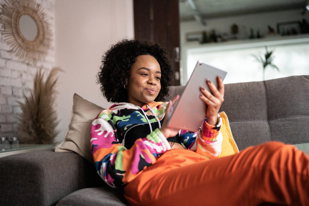 Jovem usando um tablet digital em casa.