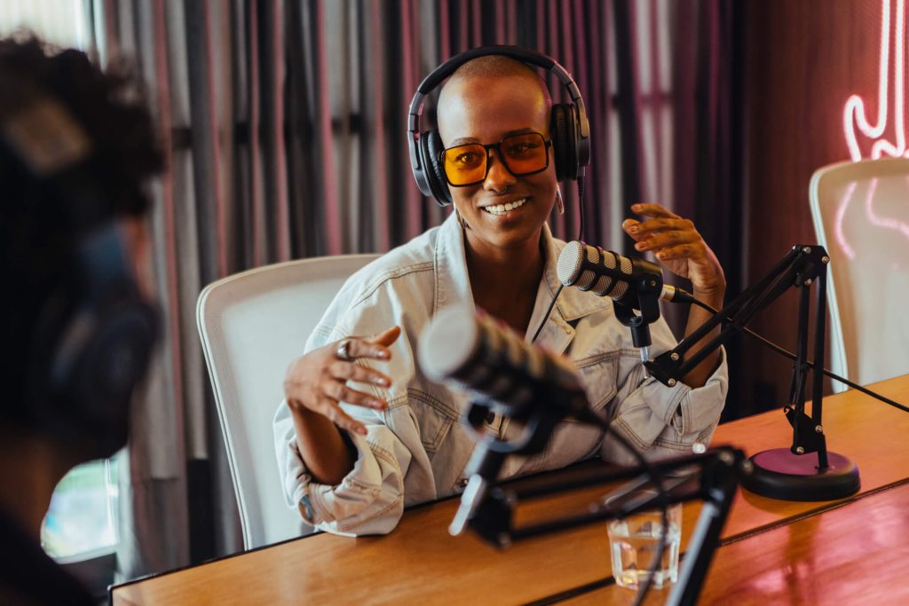 Jovem feliz gravando podcast com co-apresentador em estúdio moderno.