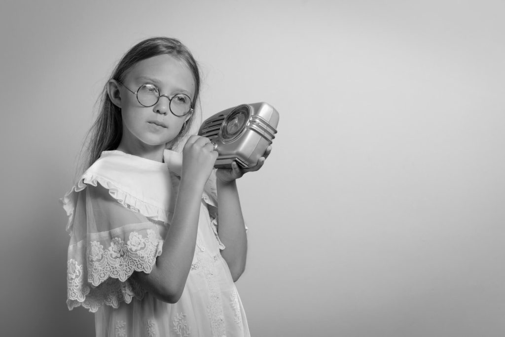 Uma adolescente do passado em preto e branco ouvindo no rádio.