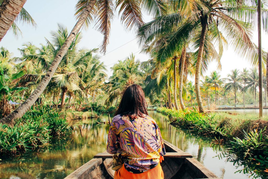 Jovem mulher está em uma canoa no meio de um rio.