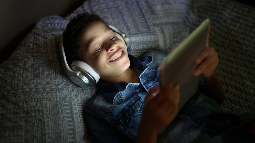 Criança assistindo a um filme usando tablet digital na cama.