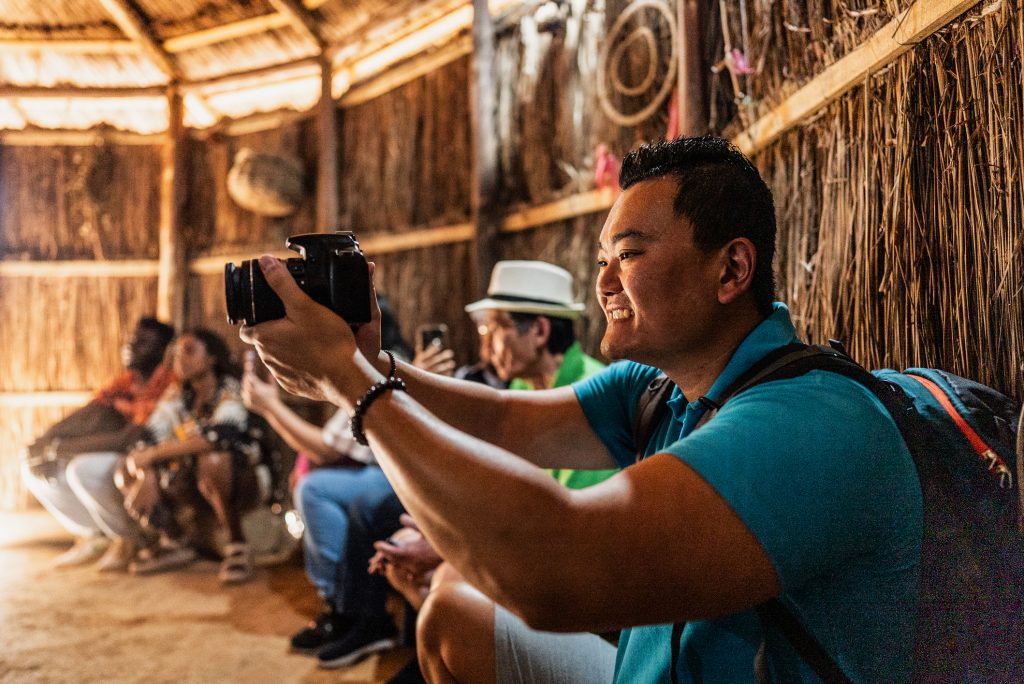 Turista fotografando indígenas durante visita turística à aldeia.