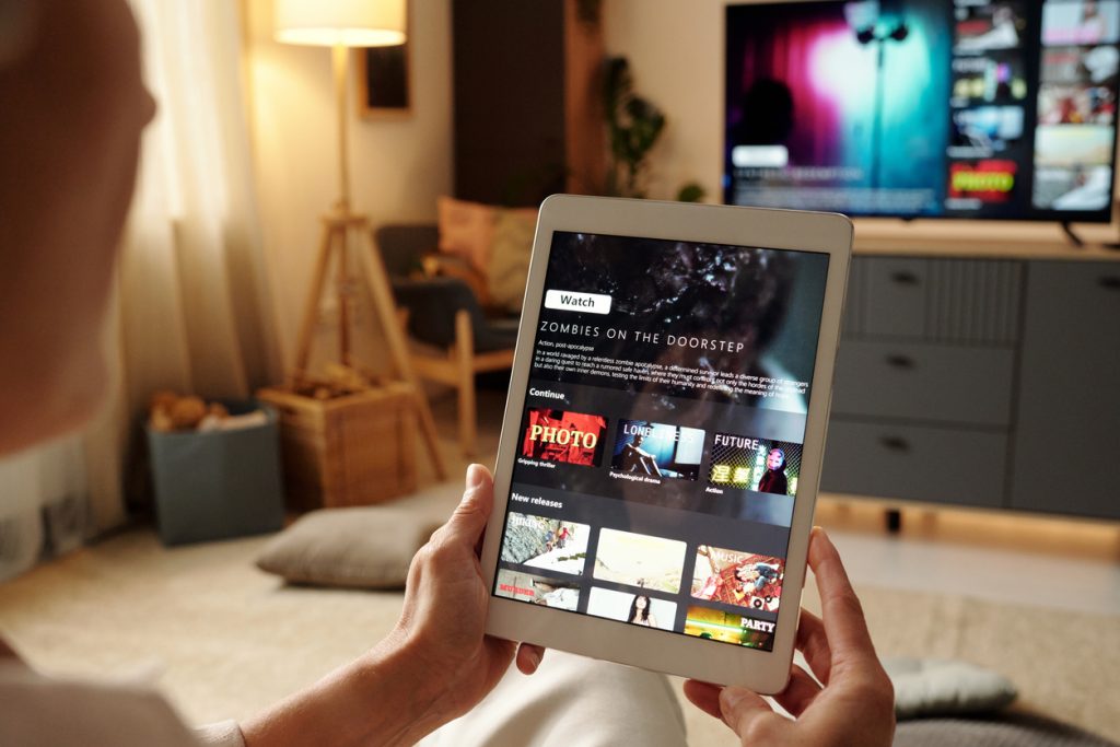 Assistindo filme no tablet na sala de estar aconchegante, o que revela o impacto do streaming em nossa sociedade.