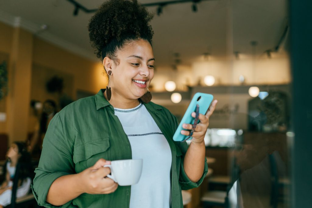 Mulher usando smartphone na loja de café. Ela ficou presa no vídeo devido a criatividade no marketing.
