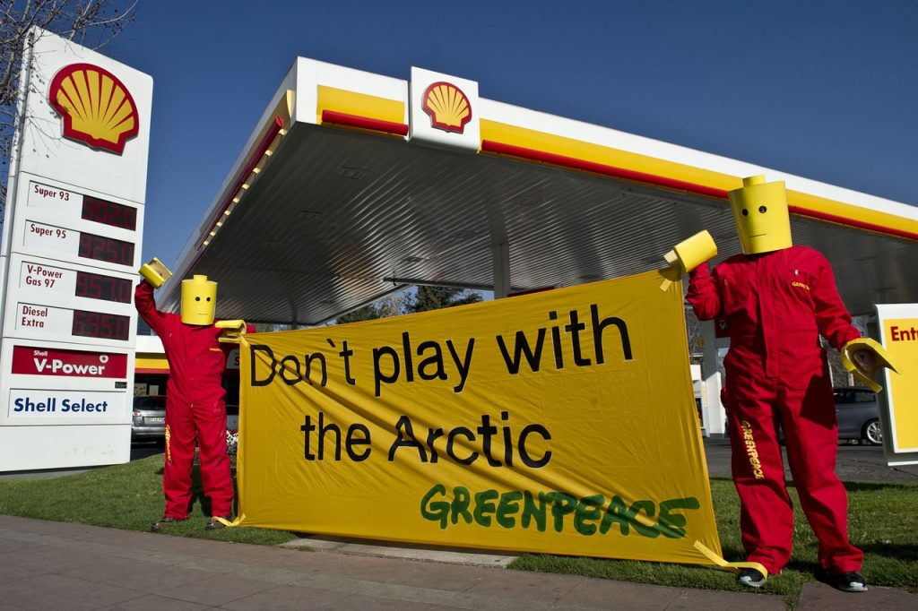 Bonecos vestido de Lego protestam em frente a um posto da Shell, representando collabs que dão errado.