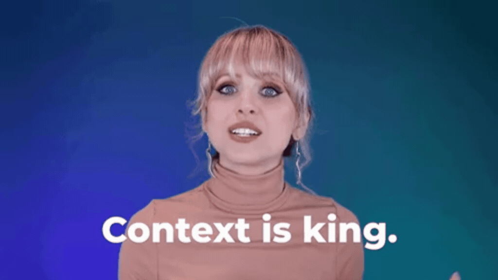GIF em loop de uma mulher loira de cabelos presos e blusa de gola alta bege, falando de forma enfática sobre um fundo degradê azul e verde. Na parte inferior, aparece a legenda em letras brancas: "Context is king." (O contexto é o rei).