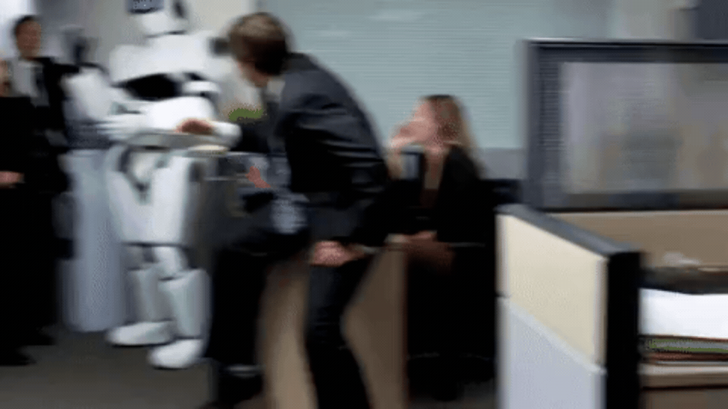 GIF animado em um ambiente de escritório corporativo. Um grande robô humanoide branco e preto caminha pelo corredor entre as baias de trabalho, esbarrando de leve em um homem de terno que tenta se desviar. Ao fundo, outros funcionários observam a cena em um ambiente dinâmico e levemente caótico.