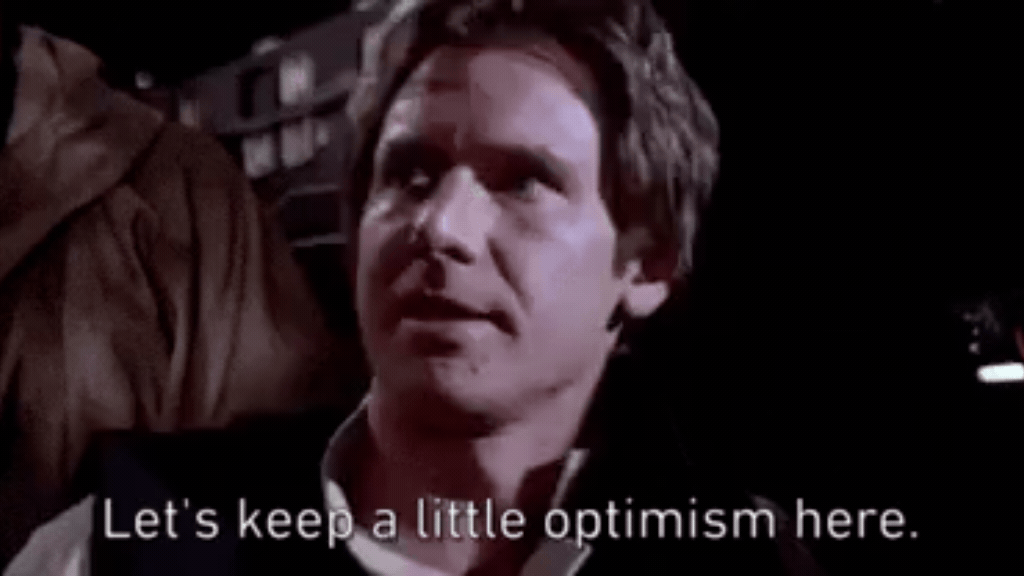 Uma captura de tela de uma cena de filme em baixa iluminação com o ator Harrison Ford focado em primeiro plano, olhando expressivamente para o lado. Na parte inferior da imagem, há uma legenda em inglês com letras brancas que diz "Let's keep a little optimism here.", remetendo ao positivismo da América Latina.