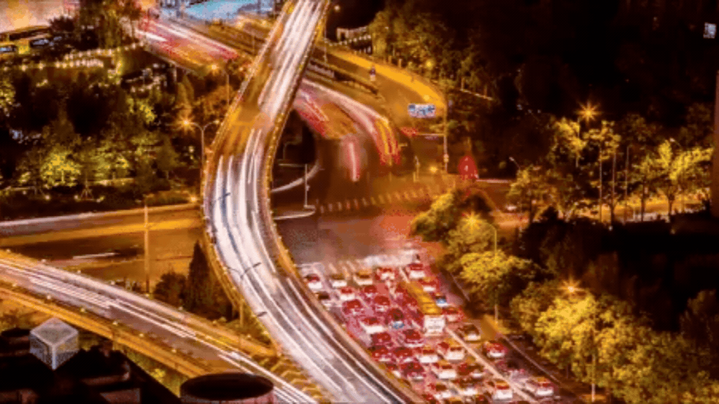 GIF com vista aérea do trânsito de uma grande cidade à noite com rastro de luzes dos carros, simbolizando as rotas do público e o direcionamento de investimentos em mídia.